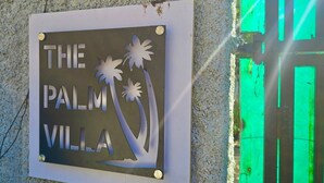 A sign with the text 'THE PALM VILLA' and palm tree silhouettes. - The Palm Villa  (Mount Abu)