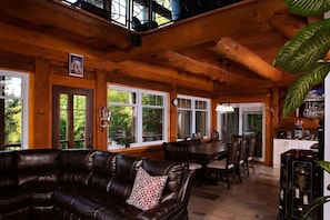 Een houten cabin met een leren bank, eettafel, stoelen en een bar.