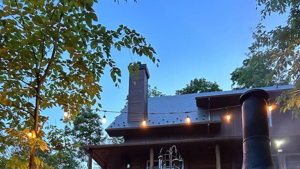 A rustic wooden house with a chimney, a stone fireplace, and string lights. - Montagnard des Pays-d`en-Haut / Private Pool & Spa / Nature & Lake (Sainte-Adèle)