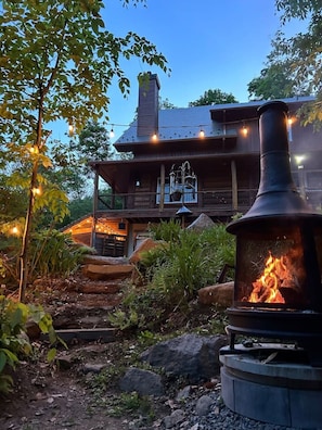A rustic wooden house with a chimney, a stone fireplace, and string lights. - Montagnard des Pays-d`en-Haut , Private Spa (Sainte-Adèle)