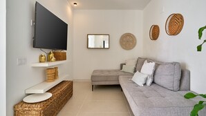 Una sala de estar con un televisor de pantalla plana, un sofá gris, una mesita y cestas decorativas.