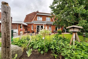 Une maison à deux étages, construite en briques, avec un jardin à l’avant.