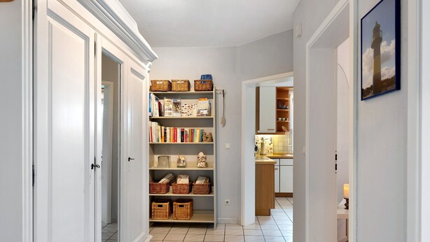 A hallway with a bookshelf, wicker baskets, and a framed picture on the wall. - Apartment 'Langusch' with Private Terrace, Private Garden and Wi-Fi (Loose)