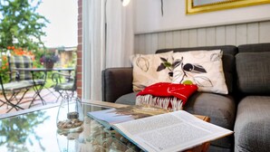 A room with a glass table, a book, a candle, and a sofa with patterned pillows. - Apartment 'Langusch' with Private Terrace, Private Garden and Wi-Fi (Loose)