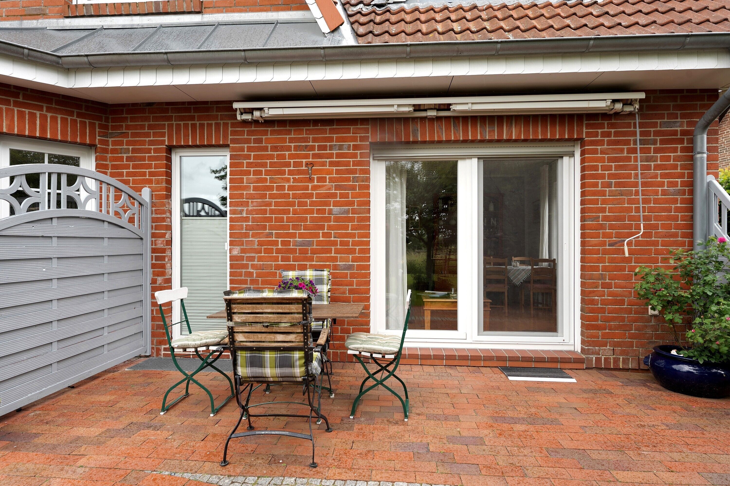 Une maison en briques avec un patio, une porte-fenêtre coulissante et une plante en pot.