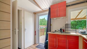 A compact kitchen with a red cabinet, a window, and a door leading to a balcony.