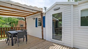 A covered outdoor area with a table and chairs, a brick wall, and a white building with a sign.