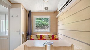 A compact room with a table, bench, and window overlooking greenery.