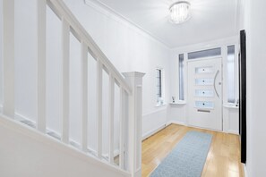 Ein Flur mit weißen Wänden, Holzboden und einem blau gemusterten Teppich.