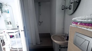 Un baño moderno con ducha, lavamanos e inodoro.