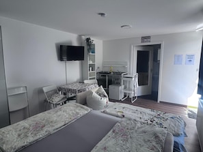 Une chambre d’hôtel équipée d’un lit, d’un bureau, d’une chaise, d’une télévision et d’une kitchenette.