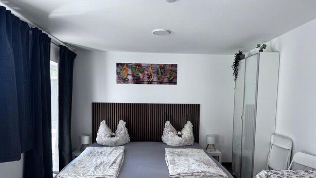 Un dormitorio moderno con una cama grande, mesitas de noche, un armario y un cuadro en la pared.