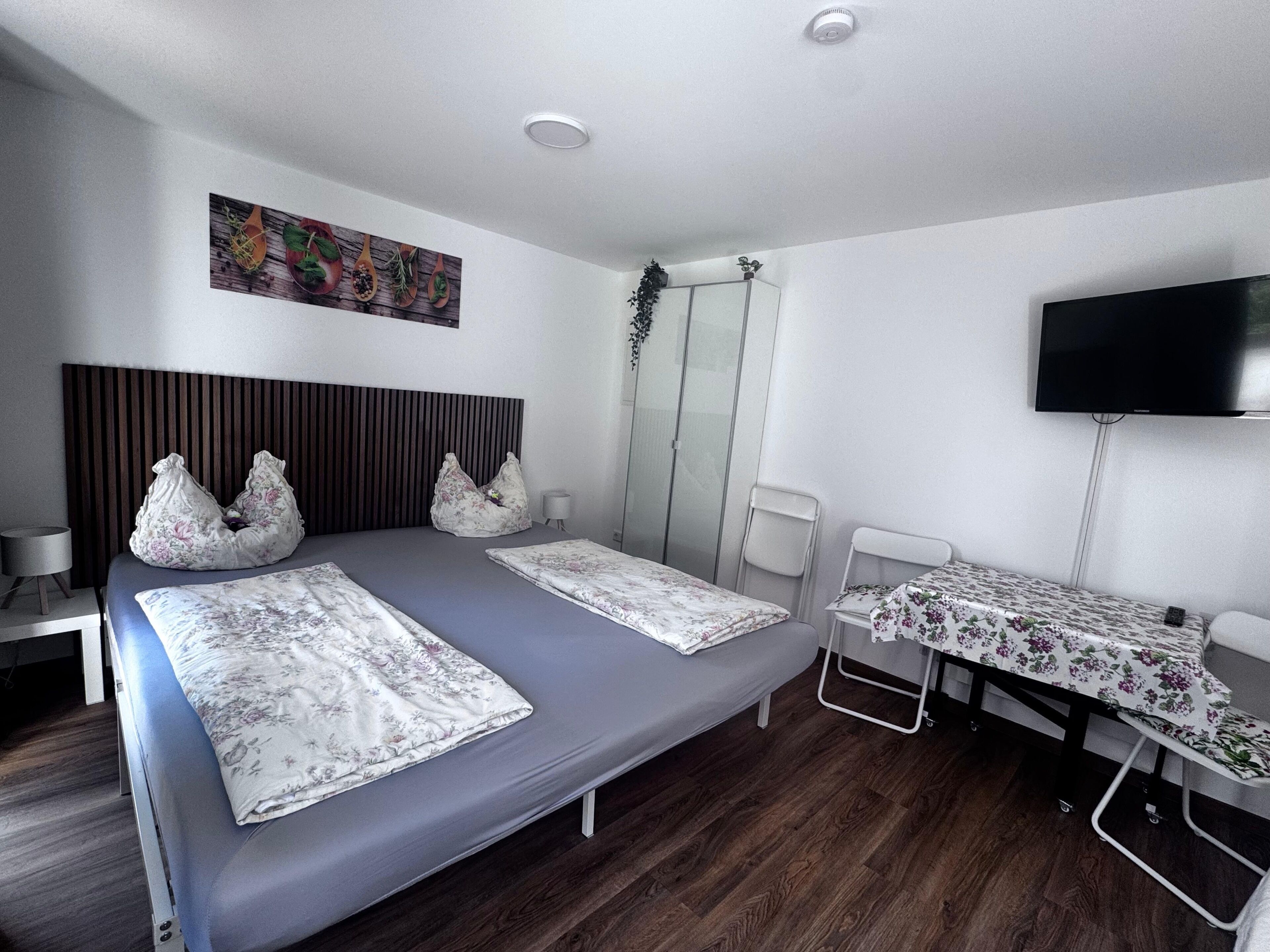 Une chambre d’hôtel avec un grand lit, une télévision, une petite table et un espace douche.