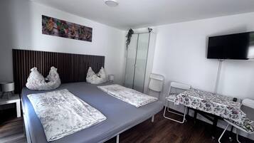 Une chambre d’hôtel avec un grand lit, une télévision, une petite table et un espace douche.