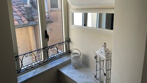 A balcony with a view of a building's exterior, a white lantern, and a small white basket. - Casa Mariuccia – 3 Bedrooms – In the Heart of Lucca (Lucca)