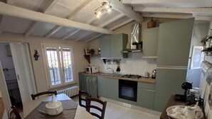 A kitchen with a dining table, chairs, a stove, and a microwave. - Casa Mariuccia – 3 Bedrooms – In the Heart of Lucca (Lucca)