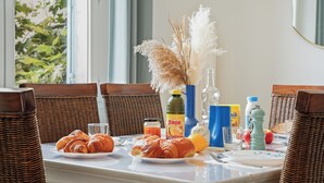 A breakfast table with croissants, a bottle of orange juice, a glass, and a vase with pampas grass. - Renovated T3 in Mourillon with balcony - Beaches on foot, premium location in Toulon (Toulon)