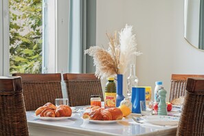 A breakfast table with croissants, a bottle of orange juice, a glass, and a vase with pampas grass. - Renovated T3 in Mourillon with balcony - Beaches on foot, premium location in Toulon (Toulon)