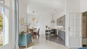 A modern kitchen with a central island, a dining area with a table and chairs, and a large window with curtains. - Renovated T3 in Mourillon with balcony - Beaches on foot, premium location in Toulon (Toulon)