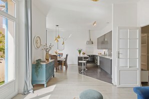 A modern kitchen with a central island, a dining area with a table and chairs, and a large window with curtains. - Renovated T3 in Mourillon with balcony - Beaches on foot, premium location in Toulon (Toulon)