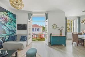 A modern living room with a sofa, a dining table, and a view of a courtyard. - Renovated T3 in Mourillon with balcony - Beaches on foot, premium location in Toulon (Toulon)