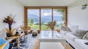 Una sala de estar con un ventanal grande, muebles de mimbre, un sofá blanco y una mesa de centro.