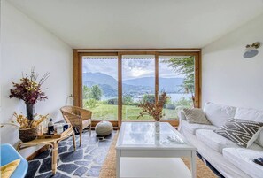 Ein Wohnzimmer mit großem Fenster, Korbmöbeln, einem weißen Sofa und einem Couchtisch.