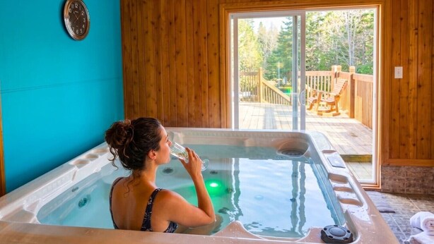Une femme dans un bain à remous, avec vue sur une terrasse en bois et un espace extérieur.
