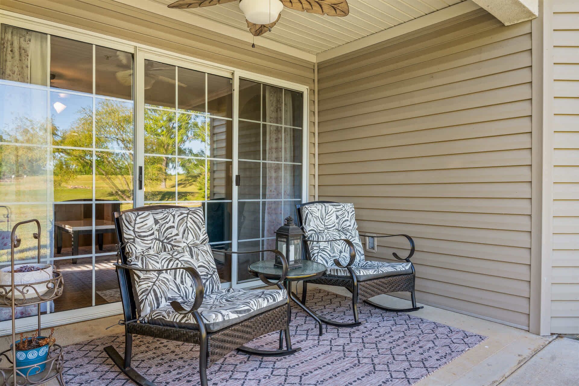 A covered porch with two rocking chairs, a small table, and a potted plant.