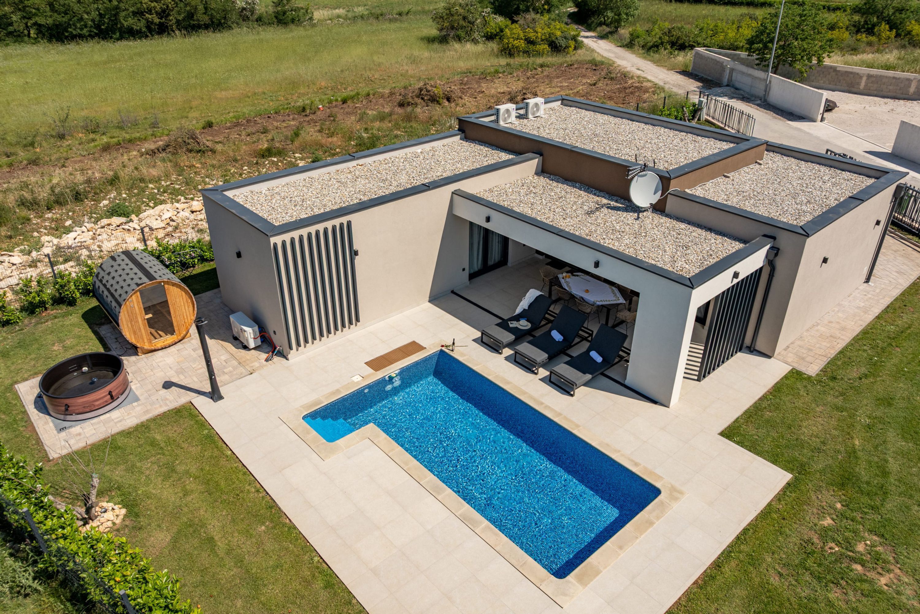 A modern house with a swimming pool, outdoor seating, and a hot tub.