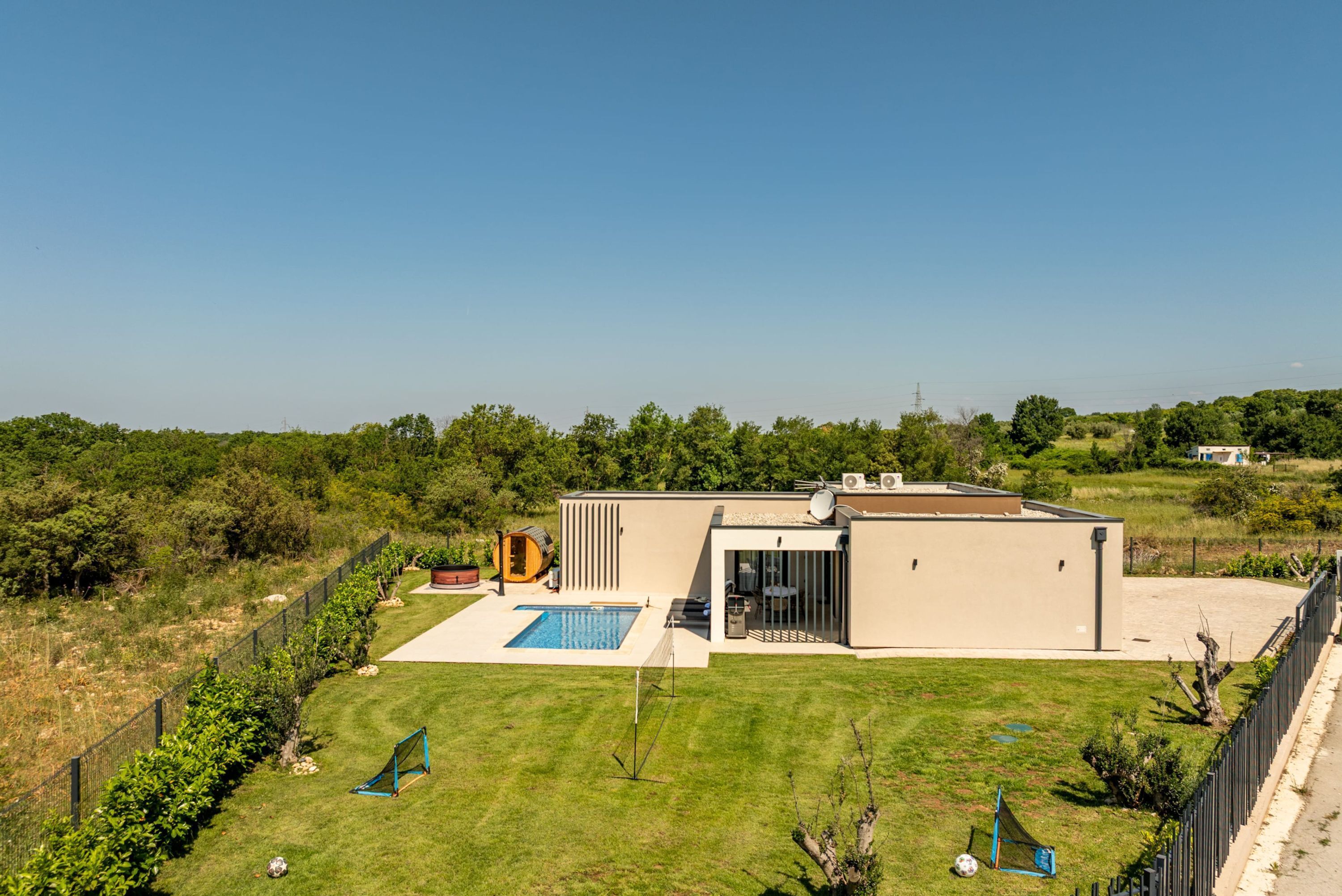 A modern house with a swimming pool, a fenced yard, and a clear view of the surrounding landscape.