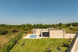 Ein modernes Haus mit Swimmingpool, umzäunter Garten und freiem Blick auf die umliegende Landschaft.
