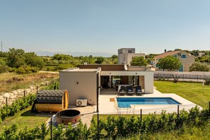 Ein modernes Haus mit Swimmingpool, Sitzgelegenheit im Freien und Blick auf die Landschaft.