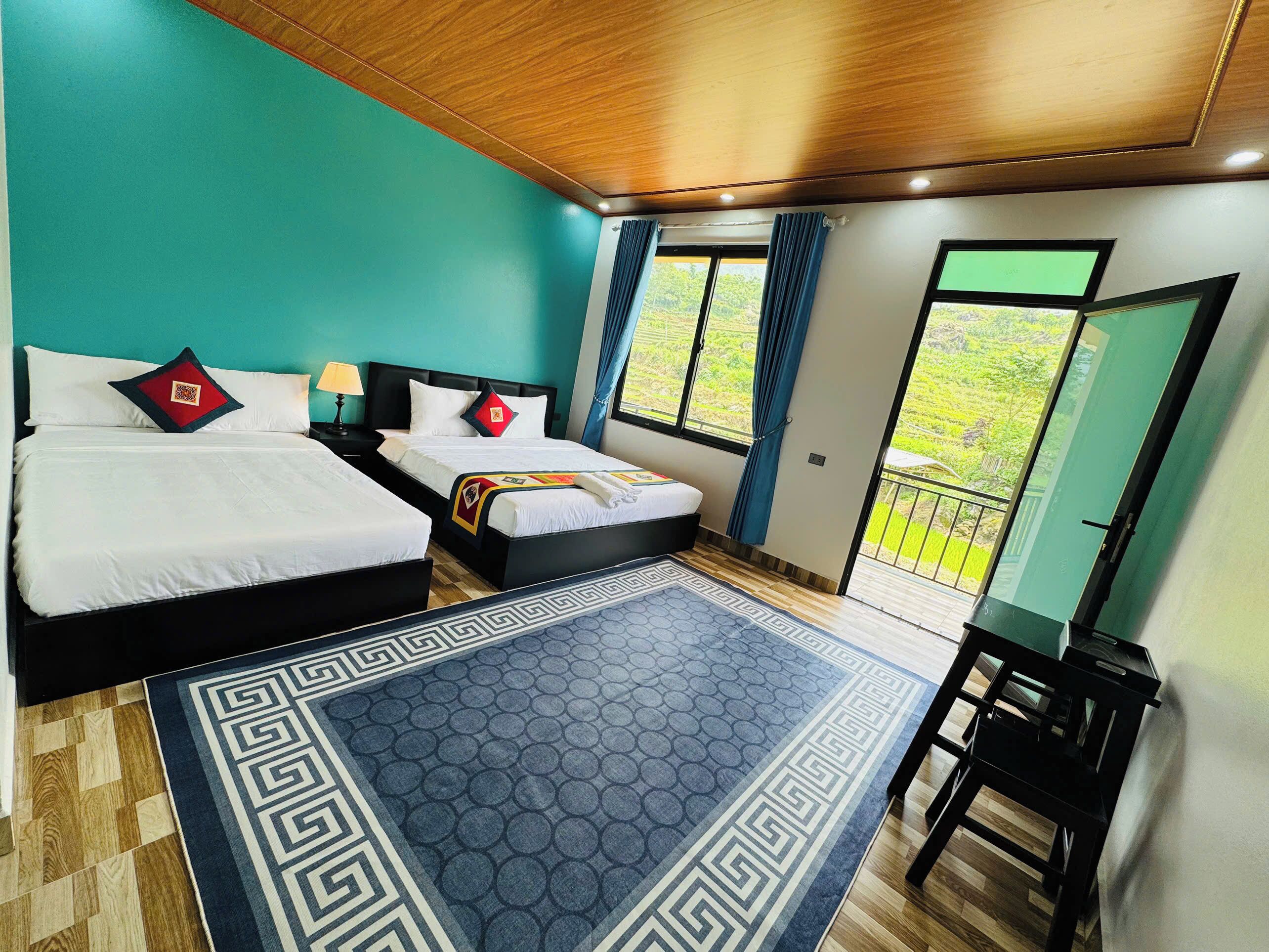 Een kamer met twee bedden, een groot raam en uitzicht op groen.