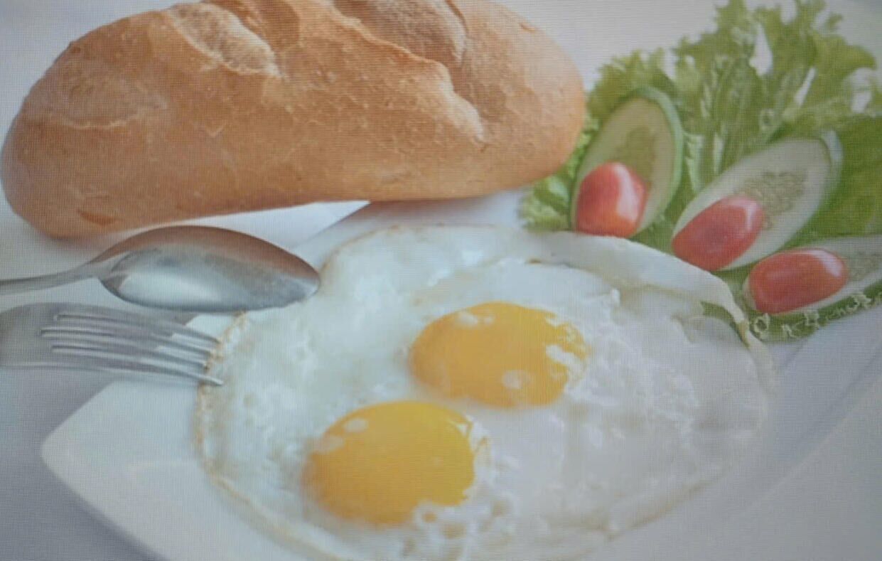 A plate with a fried egg, a piece of bread, and a side salad.