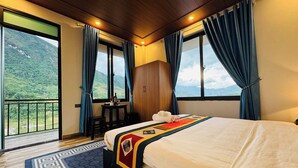 Ein Hotelzimmer mit Bett, Tisch mit Stühlen, Bergblick und einem Balkon.