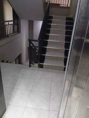 A staircase with black railings and a tiled floor. - Cozy 1 Bedroom apartment near JKIA and the SGR (Nairobi)