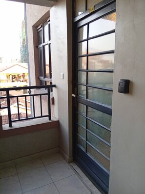 A balcony with a metal railing, a large window with multiple panes, and a door with a handle. - Cozy 1 Bedroom apartment near JKIA and the SGR (Nairobi)