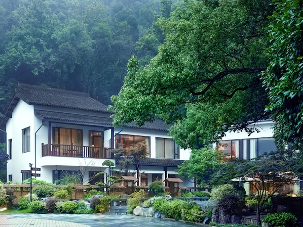 A traditional Japanese-style building with a courtyard, wooden fences, and a koi pond.