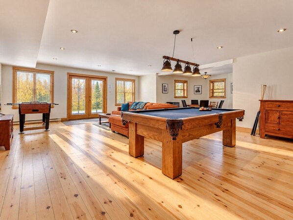 Une pièce spacieuse équipée d’une table de billard, d’un canapé et d’une table de jeu de flipper.