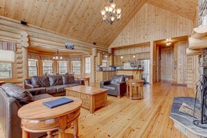 A log cabin interior with a living room, kitchen, and fireplace. - Lynx 72 | Private SPA | Heated Pool | GYM (Mille-Isles)