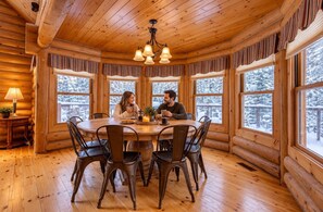 L’intérieur d’un chalet chaleureux, avec une table à manger en bois, des chaises et un lustre.