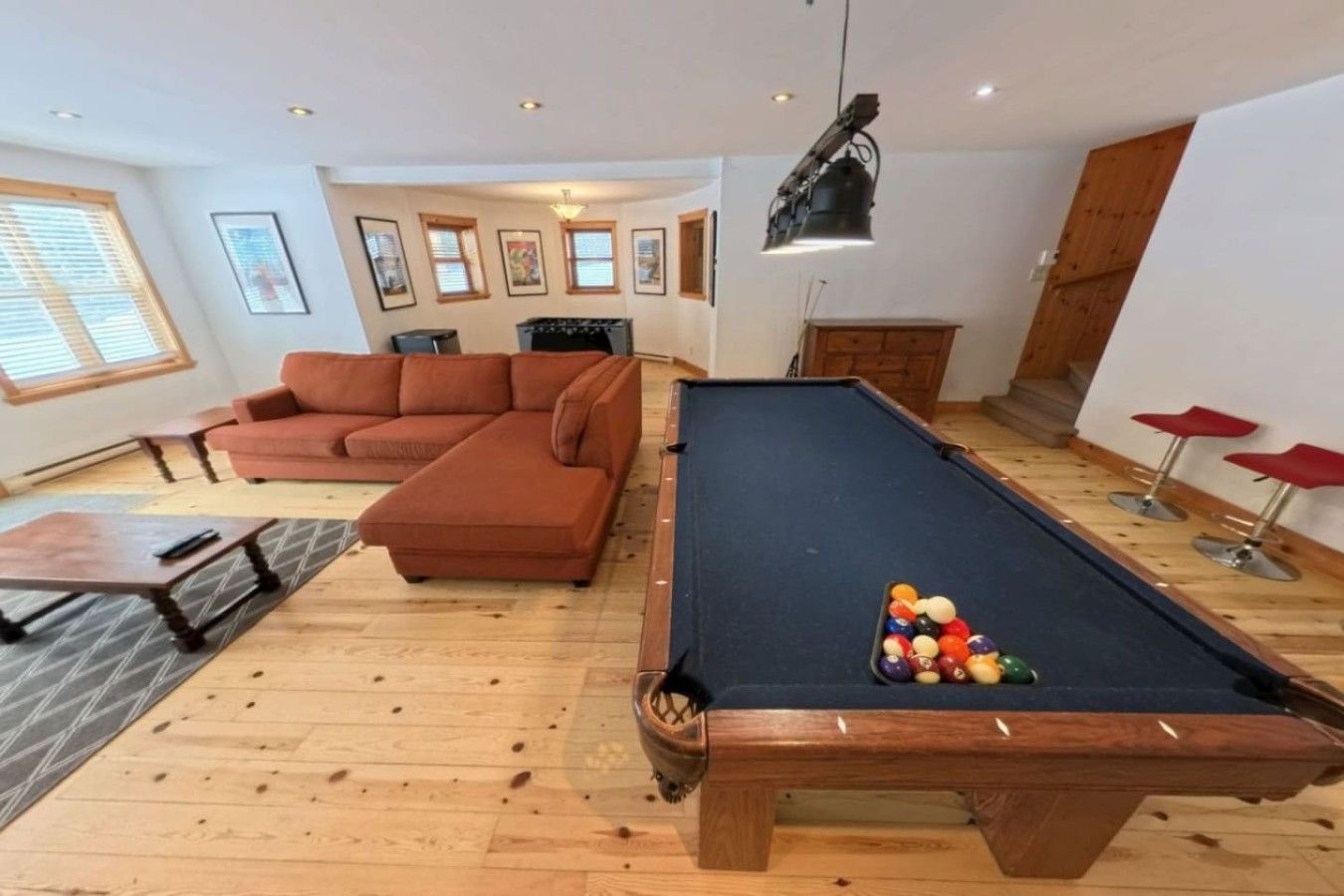 Una sala de estar con mesa de billar, un sofá y un soporte para billares.