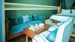 A hotel room with a sofa, a bed, a coffee table with teapots, and a nightstand. - Shigatse Summer Palace Healing Hotel (Shigatse)
