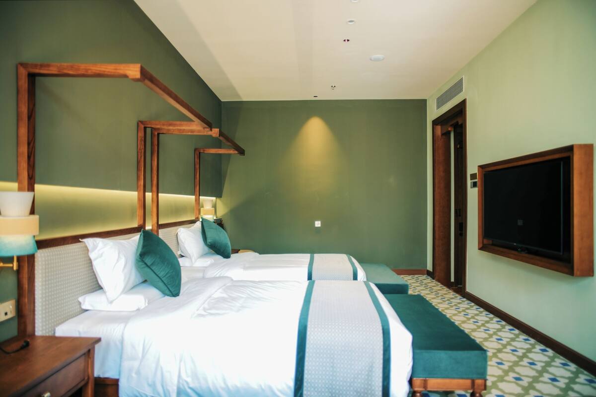 Una habitación de hotel con dos camas, televisión, mesita de noche y suelo estampado.