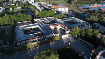 Vista aérea de un complejo con varias edificaciones, incluyendo una estructura central con patio interior y edificios circundantes con tejados rojos.