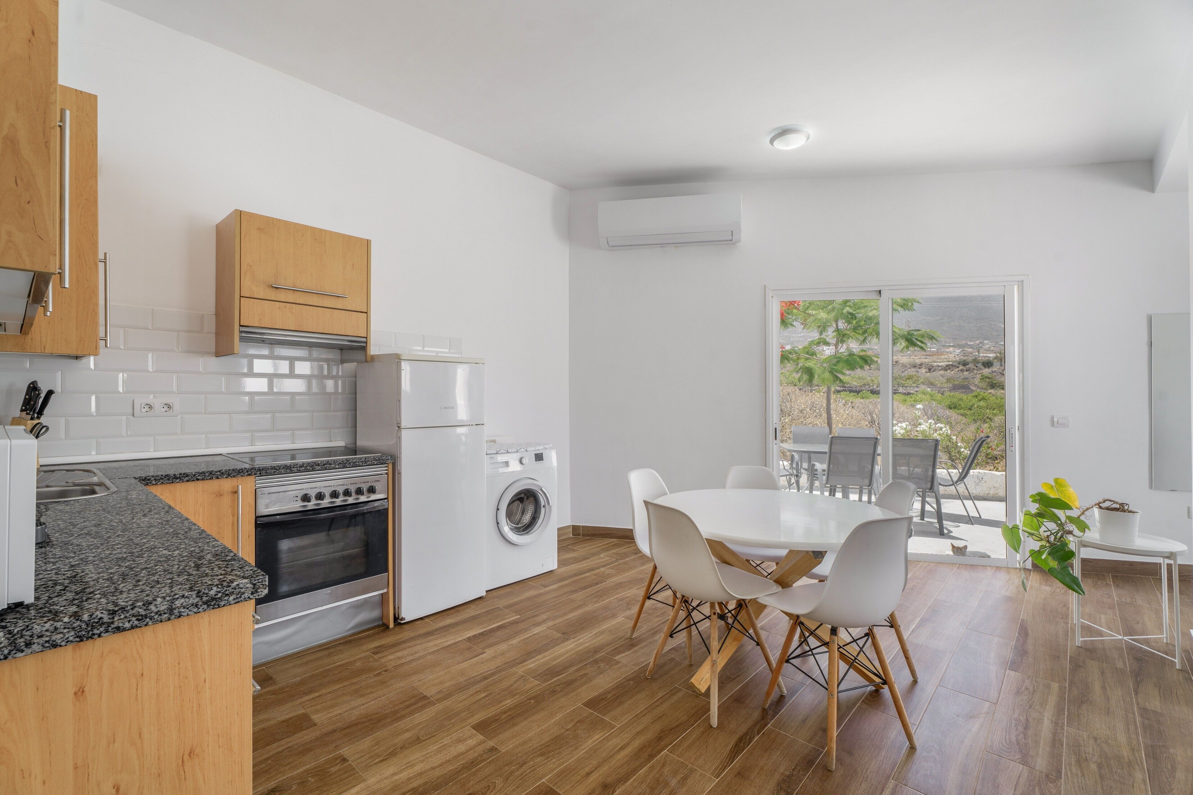 A modern kitchen with granite countertops, a built-in oven, and a washing machine.