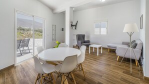 A spacious living area with a round table, chairs, a sofa, and a lamp.