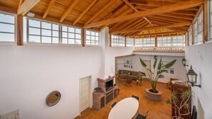 Un intérieur spacieux avec de hauts plafonds, de grandes fenêtres, une cheminée et un coin repas.
