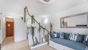 En moderne stue med sofa, spejl og en dekorativ plantevæg.